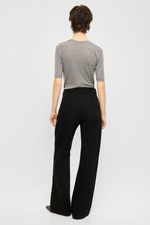 A model shown from the back wearing a gray short-sleeve knit top and black wide-leg trousers, photographed against a clean light gray studio background.